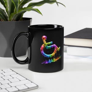 May include: Black coffee mug featuring a colorful, rainbow-hued wheelchair symbol. The design has a liquid, dripping effect. The mug has a black handle and a glossy finish, suitable for hot or cold beverages.