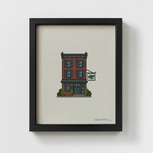 Op de afbeelding: Een ingelijste illustratie van een bakstenen gebouw met een groen bord waarop "MacLaren's Pub" staat. Het gebouw heeft een bruine deur en twee ramen op elke verdieping. De illustratie is op een beige achtergrond.