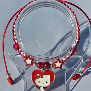 Pulseras tejidas a mano, con dije Hello kitty en forma de corazón en tonos rojo y blanco :)