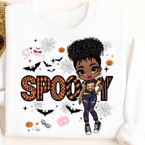 Peut inclure: Sweat-shirt blanc avec un motif sur le thème d'Halloween. Le motif présente une fille de dessin animé, le mot "SPOO-Y" en imprimé léopard et à carreaux orange, des chauves-souris, des toiles d'araignées et des citrouilles. La fille porte un t-shirt noir avec un motif de citrouille.