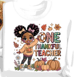 Peut inclure: Sweat-shirt blanc avec une illustration de dessin animé d'une jeune fille en pull citrouille. Le texte dit "ONE THANKFUL TEACHER" avec des graphismes sur le thème de l'automne, dont des citrouilles et des feuilles.