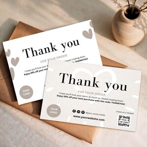 Peut inclure: Deux cartes de remerciement blanches avec un motif de cœur et les mots "Thank you" en noir. Les cartes sont sur une enveloppe marron. Les cartes incluent également le texte "FOR YOUR ORDER!" et "Enjoy 20% off your next purchase".