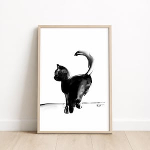 Puede incluir: Una lámina enmarcada con una ilustración en tinta negra de un gato visto desde atrás. El gato tiene la cola curvada y está situado sobre una línea horizontal sencilla. La obra está dentro de un marco de madera de color claro.