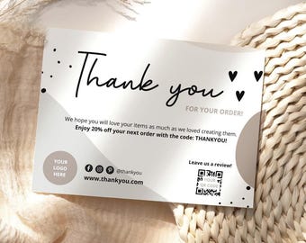 May include: A white thank you card with black text and a minimalist design. The card includes the words "Thank you" in a handwritten font, along with a discount code and social media icons. The card is on a neutral background.