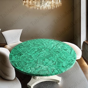 May include: A circular table featuring a striking green malachite surface. The table is supported by a white pedestal base and is surrounded by white chairs. The table's top is composed of numerous small, irregular green stone pieces.