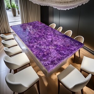 Puede incluir: Una gran mesa de comedor rectangular con una superficie texturizada de color p&uacute;rpura vibrante. La mesa est&aacute; rodeada de sillas blancas con patas de madera. El texto "TableAndLegs" es visible en la superficie de la mesa. La habitaci&oacute;n tiene un dise&ntilde;o moderno.