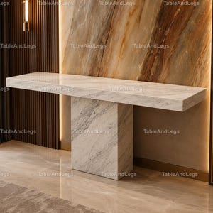 Pode incluir: Uma moderna mesa consola de mármore com um tampo retangular e uma base retangular única e espessa. A mesa é branca com veios cinzentos, e o fundo apresenta uma parede de mármore e um painel de madeira escura. A imagem está marcada com a palavra "TableAndLegs".