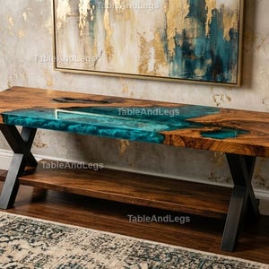 May include: A handcrafted wooden coffee table with a turquoise epoxy resin river. The table features a lower shelf and black metal legs. The wood has a natural grain pattern, and the table is approximately 60 inches long.