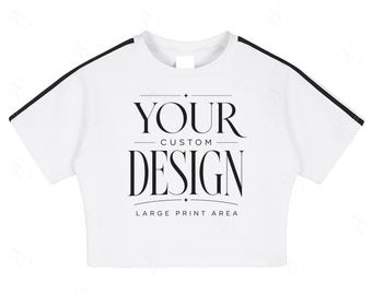 Może przedstawiać: Biały top z czarnymi paskami na rękawach. Koszulka zawiera napis "YOUR CUSTOM DESIGN" pogrubioną, elegancką czcionką, z napisem "LARGE PRINT AREA" poniżej. Jest to odzież codzienna.