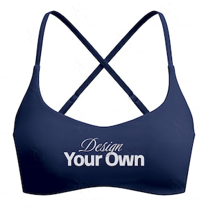 May include: A navy blue sports bra with a criss-cross back design. The bra features thin straps and the words "Design Your Own" in white script across the front.