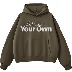 May include: An olive green hooded sweatshirt featuring a front kangaroo pocket and long sleeves. The chest displays the white text "Design Your Own" with the word "Design" in a cursive script font and "Your Own" in a bold, sans-serif typeface.