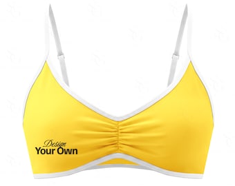 Może przedstawiać: Żółty top od bikini z białym wykończeniem i regulowanymi ramiączkami. Top ma marszczony środek i czarny napis "Design Your Own".
