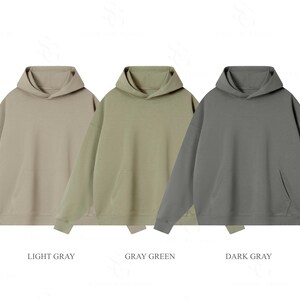 Pu&ograve; includere: Tre felpe con cappuccio a maniche lunghe dotate di una tasca a marsupio frontale e polsini a coste. Le felpe sono presentate in tre colori distinti etichettati come light gray, gray green e dark gray, con un design a tinta unita.