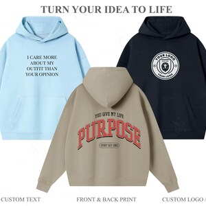 Pu&ograve; includere: Tre felpe con cappuccio in azzurro, beige e nero. La felpa azzurra presenta il testo I CARE MORE ABOUT MY OUTFIT THAN YOUR OPINION. La felpa beige mostra il testo YOU GIVE MY LIFE PURPOSE EVERY DAY LORD. La felpa nera ha un logo circolare con un leone e il testo YOUR LOGO.
