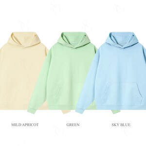Pu&ograve; includere: Tre felpe con cappuccio a maniche lunghe in colori pastello. La felpa a sinistra &egrave; etichettata MILD APRICOT, quella centrale GREEN e quella a destra SKY BLUE. Ogni felpa &egrave; dotata di un cappuccio e di una tasca a marsupio sul davanti.