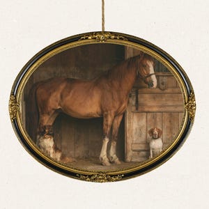 May include: An oval-shaped wall hanging featuring a framed print of a brown horse standing in a wooden stable stall with a small brown and white dog sitting near its legs and another dog resting on the ground, all enclosed in a black and gold frame.