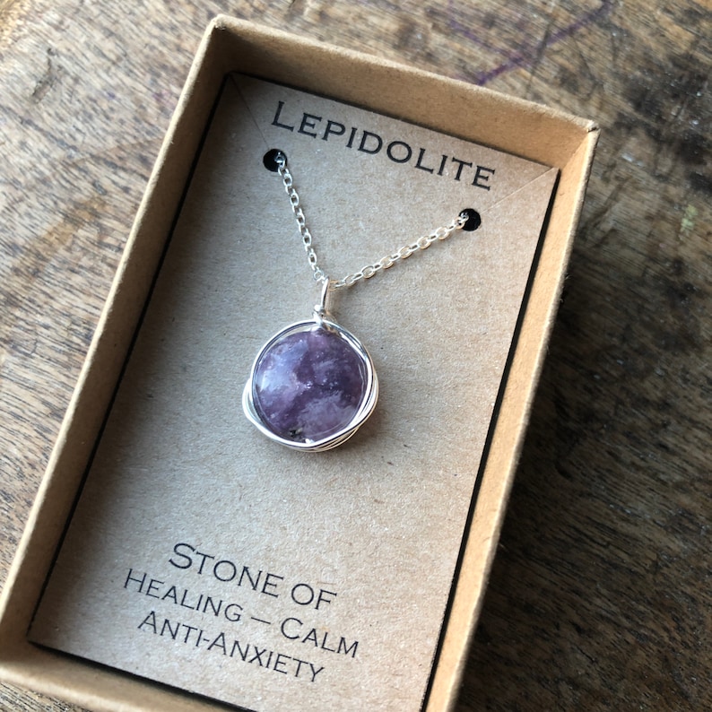 Pu&ograve; includere: Una collana a catena d'argento con un ciondolo in pietra di lepidolita viola avvolto in filo d'argento. La collana &egrave; in una piccola scatola con il testo "LEPIDOLITE" e "PIETRA DI GUARIGIONE - CALMA ANTI-ANSIA".