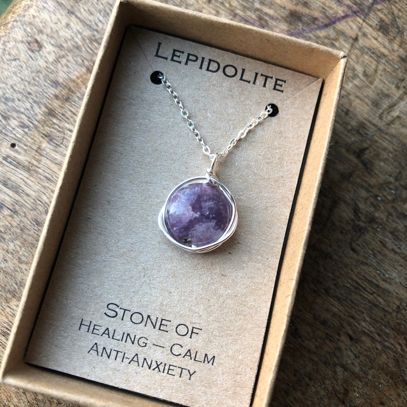Pu&ograve; includere: Una collana a catena d'argento con un ciondolo in pietra di lepidolita viola avvolto in filo d'argento. La collana &egrave; in una scatola con il testo "LEPIDOLITE" e "PIETRA DI GUARIGIONE - CALMA ANTI-ANSIA".