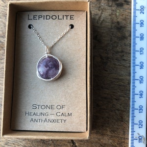 Pu&ograve; includere: Una collana a catena d'argento con un ciondolo rotondo in pietra di lepidolita viola. Il ciondolo &egrave; avvolto in filo d'argento. La collana &egrave; in una piccola scatola con le parole "LEPIDOLITE", "PIETRA DI", "GUARIGIONE - CALMA", e "ANTI-ANSIA" stampate su di essa.