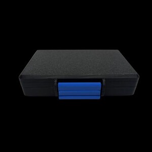 May include: A rectangular black storage case with a textured surface and a bright blue plastic latch centered on the front edge. The case is closed and features a simple, functional design with clean lines and a solid, opaque construction.