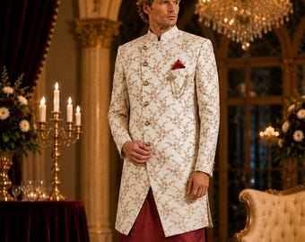 Puede incluir: Un conjunto formal con una chaqueta marfil con estampado floral, pantalones y camisa burdeos. La chaqueta de manga larga tiene un pañuelo de bolsillo rojo y una cadena dorada. Zapatos negros completan el conjunto.
