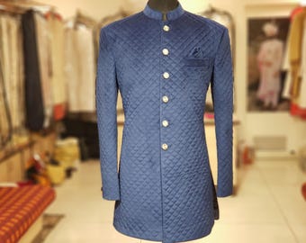 May include: A navy blue quilted jacket with a mandarin collar and decorative buttons. The long-sleeved jacket has a pocket on the chest and is displayed on a mannequin. The jacket is a formal style.