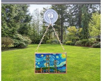 May include: A stained glass window hanging from a suction cup on a window. The window features a painting of the Golden Gate Bridge with a starry night sky in the background.