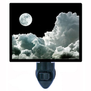 May include: A nightlight with a black and white image of a full moon and clouds in a dark sky.