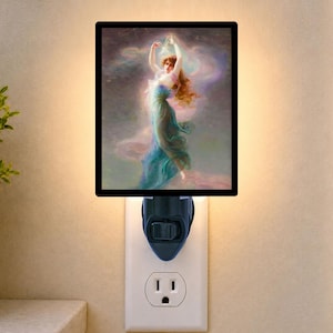 May include: A rectangular plug-in night light featuring a printed image of a figure with long hair in a flowing blue and green dress, surrounded by swirling pink and purple clouds. The light is plugged into a standard wall outlet with a black base.