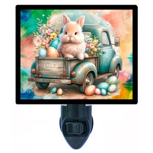May include: A night light featuring a watercolor illustration of a light blue vintage truck carrying a fluffy bunny, Easter eggs, and flowers. The truck bed has the word "Easter" on it. The background is a colorful pastel.