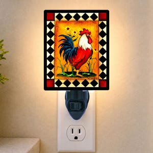 May include: A rectangular night light featuring a central illustration of a rooster with red, white, and blue plumage against a yellow background. The image is framed by a black and white diamond pattern border with red accents at the corners.