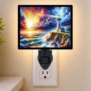 May include: A rectangular plug-in night light featuring a vibrant, colorful illustration of a lighthouse on a rocky cliffside overlooking a stormy ocean at sunset, with a black frame and a black base plugged into a standard wall outlet.