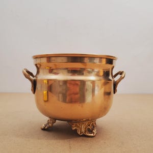 Maceta pequeña de latón vintage con patas, de metal dorado, estilo francés. Maceta pequeña de latón estilo francés vintage con asa y patas.
