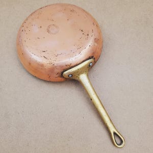 May include: A white ceramic mug with a black handle and the text "But First, Coffee" in a bold, black font. The mug is set against a blurred background, suggesting a cozy setting.