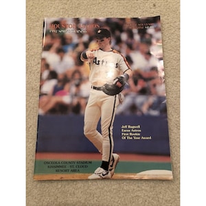 May include: A Houston Astros 1992 Spring Training official souvenir magazine featuring a baseball player in a white uniform with black trim, holding a glove. The cover includes text about Jeff Bagwell and the Osceola County Stadium location.