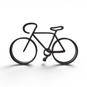 Puede incluir: Una silueta negra, plana y bidimensional de una bicicleta. El diseño presenta un contorno continuo que forma el cuadro, dos ruedas circulares, manillar, un sillín y un pedal único. El objeto está acabado en un color negro mate sólido.