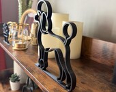 Elegant black poodle line art sculpture on a shelf, with warm-toned home accessories creating a cozy, modern look.