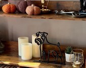 Black Schnauzer line art dog sculpture, minimalist handmade shelf decor, placed next to candles and books.