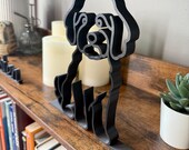 Angled view of the Mini Goldendoodle sculpture highlighting its dimensional 3D lines and modern minimalist design, styled with books and home accessories.
