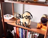 Styled lifestyle scene of a Bichon Frise line art sculpture on a wooden display shelf with vintage books, candles, and decorative accents — modern minimalist Bichon Frise home decor and a heartfelt Bichon gift idea for shelves, mantels, and white fluffy dog lover homes.