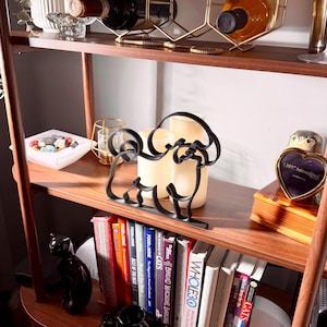 Styled lifestyle scene of a Bichon Frise line art sculpture on a wooden display shelf with vintage books, candles, and decorative accents — modern minimalist Bichon Frise home decor and a heartfelt Bichon gift idea for shelves, mantels, and white fluffy dog lover homes.