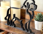 Side angle view of a Newfoundland Dog line art sculpture in matte black finish, styled on a shelf with candles and greenery. This modern minimalist decor piece is 3D printed for crisp detail and smooth edges. Perfect gift for dog lovers, Newfoundland enthusiasts, or pet parents who appreciate contemporary design. Lightweight, durable, and handmade with care, it blends effortlessly into modern, Scandinavian, or eclectic home interiors.