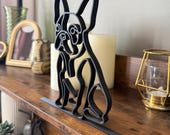 Modern black French Bulldog line art sculpture on a shelf, styled with warm-toned home decor and minimalist accessories.