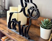 French Bulldog sculpture in sleek matte black 3D printed line art, displayed at an angle on a wooden shelf with books, candles, and decor. Perfect Frenchie dog lover gift, pet parent keepsake, or modern shelf accent. Minimalist line art home decor designed to capture the playful yet loyal French Bulldog personality. Lightweight and durable with a smooth finish, ideal for housewarming, birthdays, or holidays.