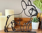 Minimalist French Bulldog line art sculpture in matte black, styled on a wooden shelf with candles and a succulent plant. Modern 3D printed Frenchie dog decor, perfect for French Bulldog lovers, pet parents, or gift giving. Unique home accent for shelves, desks, or mantels with a sleek, continuous line design that blends into Scandinavian, modern, or eclectic interiors. Lightweight yet durable dog lover gift.