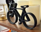Modern black bicycle line art decor on wooden shelf with soft candlelight, unique cycling gift for bike riders, cycling fans, and bicycle art collectors.