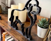 Close-up view of Newfoundland Dog line art sculpture in sleek matte black. Contemporary 3D printed pet lover decor featuring durable PLA with smooth edges and a modern silhouette. Styled with candles and greenery for an elegant shelf display. A perfect minimalist art piece for Newfoundland enthusiasts, dog lovers, or anyone looking for a handmade gift or home accent that stands out with both charm and style.