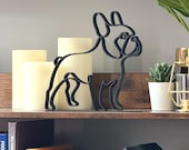 French Bulldog sculpture in single line art design, 3D printed in matte black and styled on a wooden shelf with candles, succulent, and home accents. Minimalist French Bulldog decor that perfectly captures the iconic Frenchie stance and playful character. Lightweight yet durable modern dog sculpture, perfect for Frenchie lovers, pet parents, or as a unique home gift. A stylish accent for shelves, desks, or mantels with modern flair.
