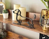 Full styled shot of miniature dachshund sculpture centered on a wooden shelf. Matte black single line dog figure for bookshelf decor, office styling, or pet memorial keepsake.