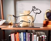 Bull terrier line art sculpture styled on a vintage wooden bookshelf with classic books, a warm amber candle, and decorative accents — minimalist 3D printed dog decor and a unique bull terrier gift idea for shelves, mantels, and modern dog lover homes.